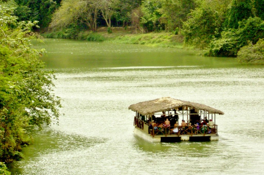 Barcaza navegando por el Río Chavón entre vegetación tropical, con brunch a bordo para los invitados de Alma